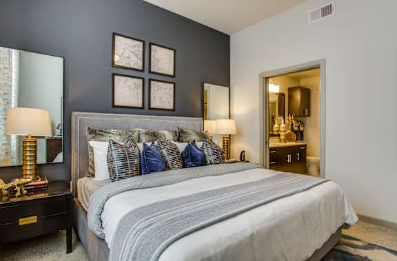 A bedroom with a large bed and a mirror on the wall.