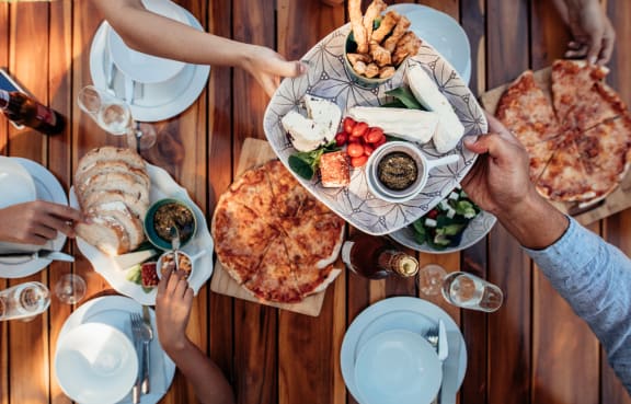 a group of people sitting around a wooden table eating food