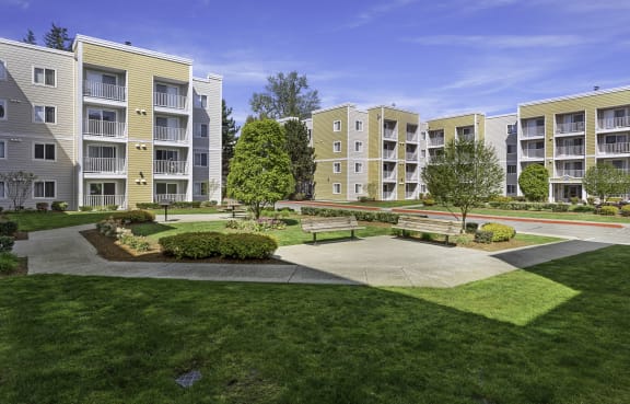 an exterior view of an apartment complex with green grass and trees  at Camelot Apartment Homes, Everett, WA, 98204