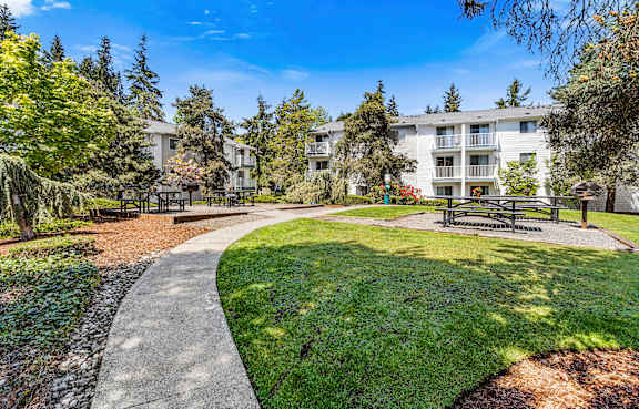 a park with benches and trees in front of an apartment building at Park 212 Apartment Homes, Washington