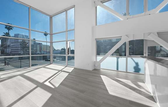 A large white room with wooden floors and large windows.