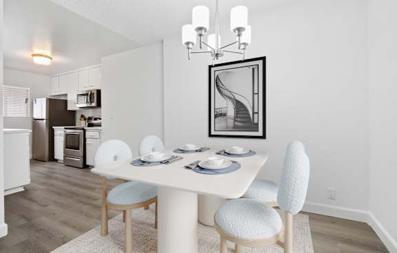 A dining room with a white table and chairs.