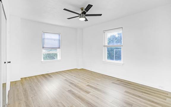 A room with a ceiling fan and two windows.at Park Wilshire, Los Angeles