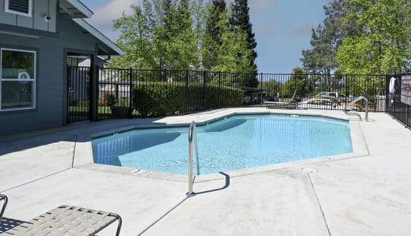 a pool with a fence around it and a house in the background