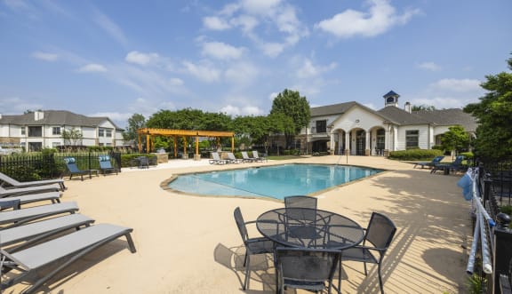 a resort style swimming pool with chaise lounge chairs and umbrellas in front of a
