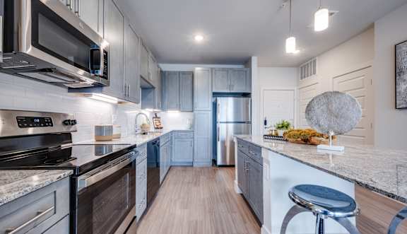 A modern kitchen with dark wood cabinets and stainless steel appliances.