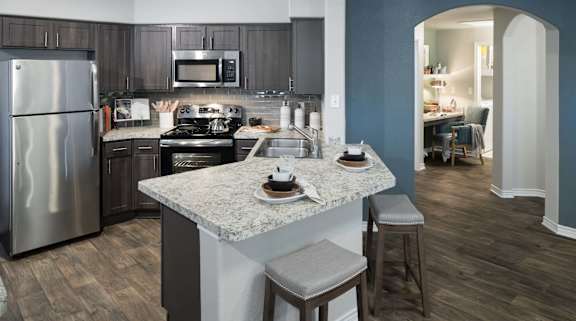 A kitchen with a marble countertop and a refrigerator.