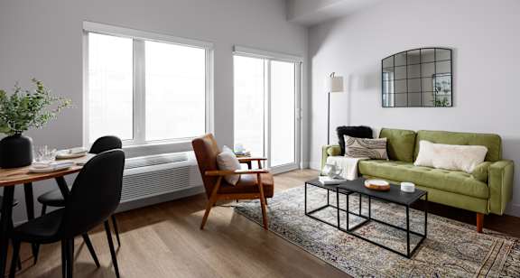 A living room with a green couch, a wooden table, and a rug.