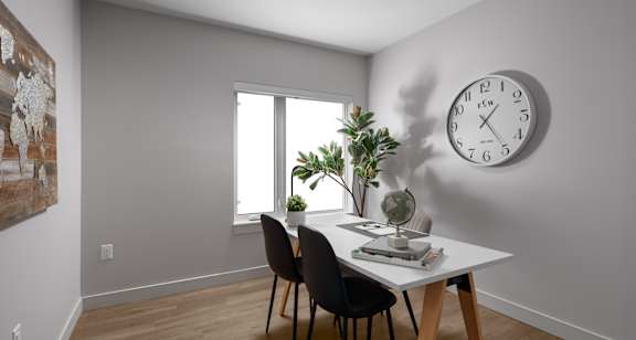 A room with a table, chairs, and a clock on the wall.