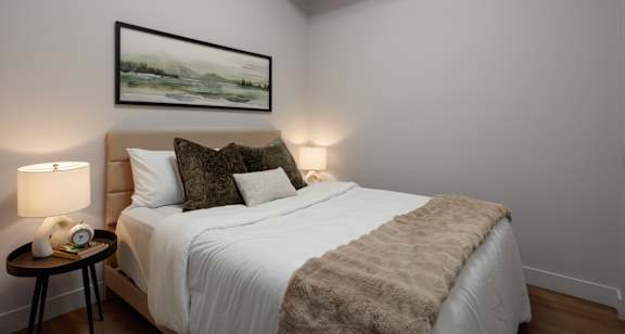 A bedroom with a large bed and a painting on the wall.