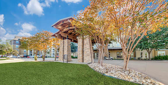 a grassy area with trees in front of a building