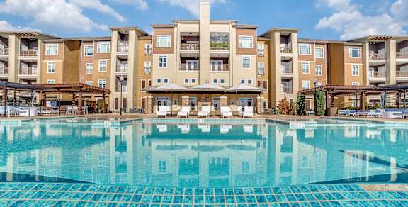 A large swimming pool in front of apartment buildings.