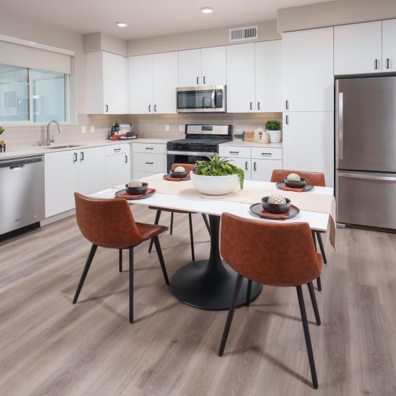 Interior of a model apartment showing kitchen with stainless steel appliances