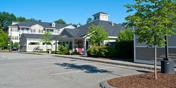 A large building with a tower and a parking lot in front.
