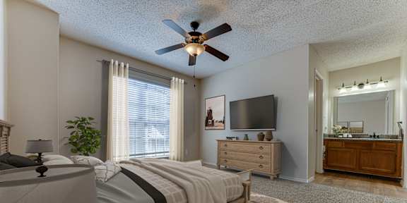 A bedroom with a bed, dresser, and ceiling fan.