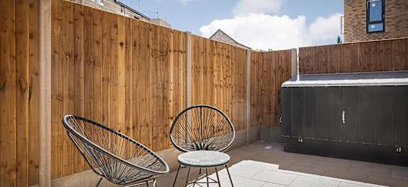 a patio with two chairs and a table in front of a wooden fence