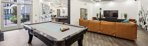 A pool table is in the middle of a room with a couch and a TV.