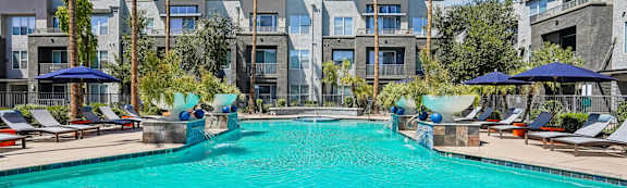 A swimming pool surrounded by palm trees and lounge chairs.