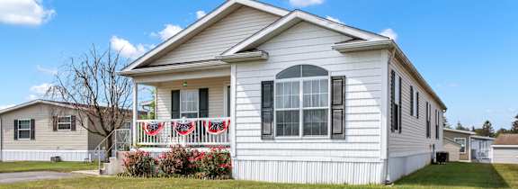 A white house with a red and white striped awning on the front porch.
