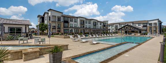 A large outdoor swimming pool surrounded by lounge chairs and umbrellas.