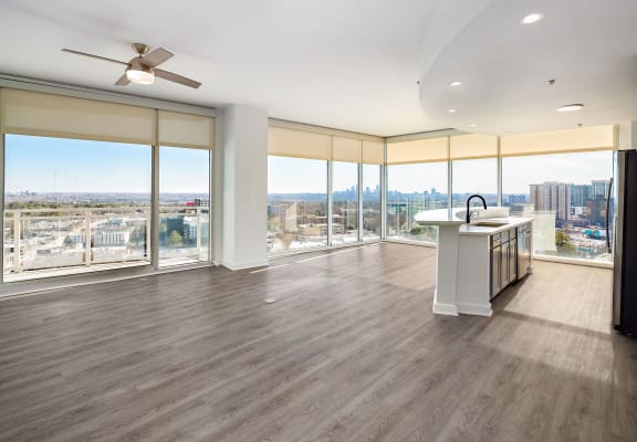 a living room with a large window overlooking a city and a kitchen