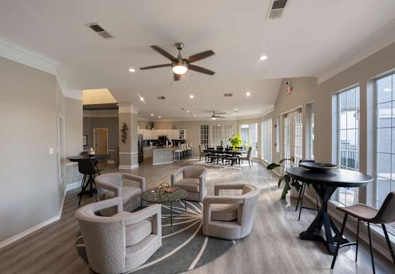 a living room with chairs and a table and a ceiling fan