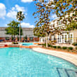 A large swimming pool in the middle of a courtyard surrounded by trees and buildings.