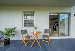 a table and two chairs sit on a balcony in front of a door at Piper Village West, Florida