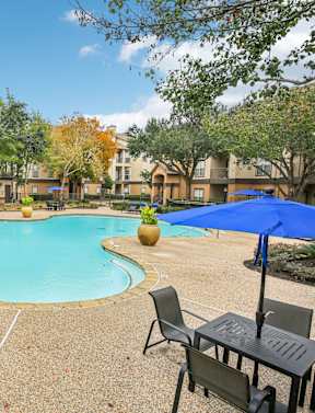 A pool surrounded by chairs and umbrellas in a sunny day.
