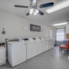 a laundry room with washers and dryers and a table with chairs  at Arbors Of Cleburne, Texas, 76033