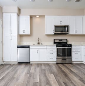 two people standing in a kitchen looking at their cell phones