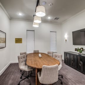 a meeting room with a table and chairs and a tv on the wall