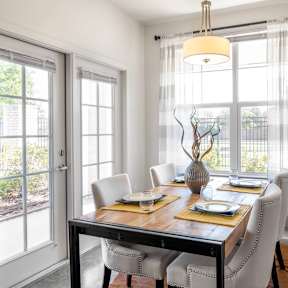 A sun filled dining room with a table set for 4 people
