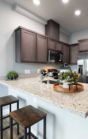 A kitchen with brown cabinets and a granite countertop at ONE18 West Street Residential Apartments, Reno Nevada