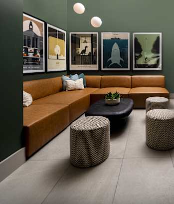 A room with a couch, a table, and a large screen displaying a forest scene.