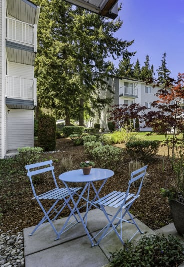 a patio with a table and chairs in front of a building