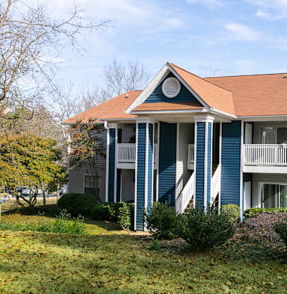an apartment building with blue siding and a brown roof
