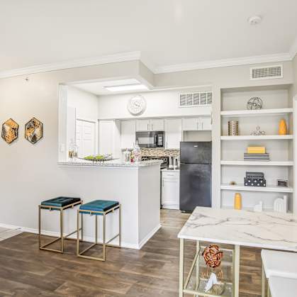 A kitchen with a white counter top and bar stools.