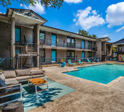 A swimming pool is surrounded by lounge chairs and umbrellas.