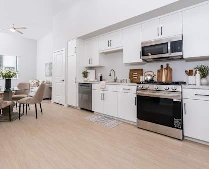 A modern kitchen with white cabinets and a wooden floor.