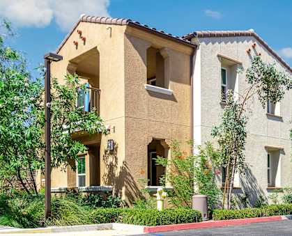 a group of apartments with trees and bushes in front of them