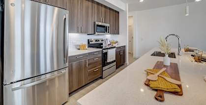 A modern kitchen with a stainless steel refrigerator and wooden cabinets.