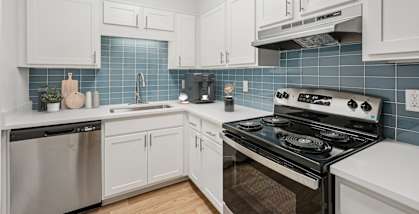 A kitchen with white cabinets and a black stove top oven.