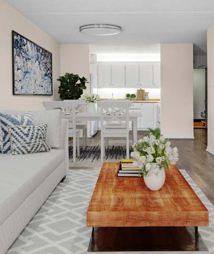 A living room with a white couch, a wooden coffee table, and a painting on the wall.