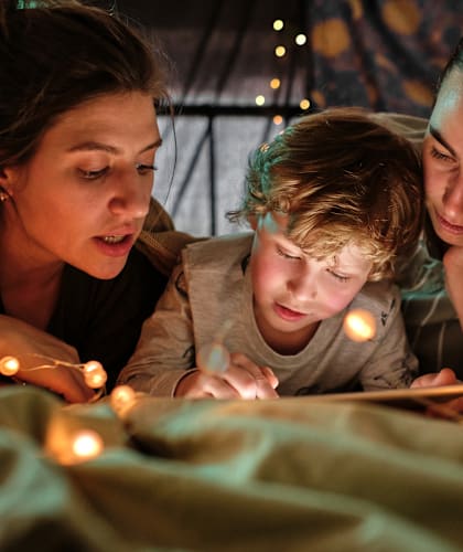 a boy and two women reading a book with lights