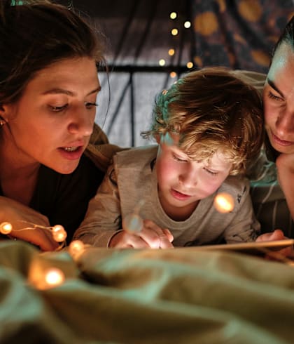 a boy and two women reading a book with lights at Waldo Heights, Kansas City, 64131