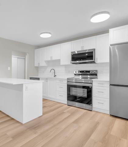 A modern kitchen with wooden floors and stainless steel appliances.
