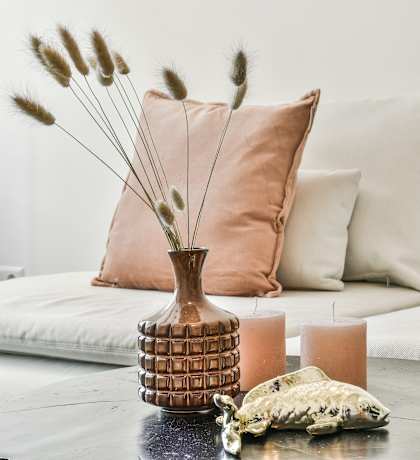 A table with a vase, candles, and a decorative item on it.