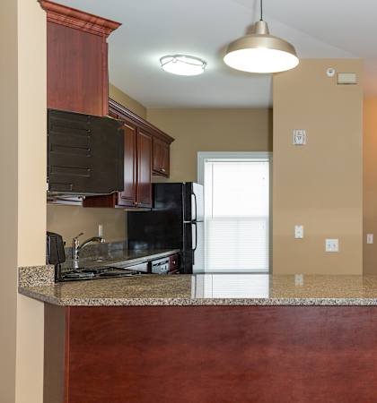 A kitchen with brown cabinets and a granite countertop.