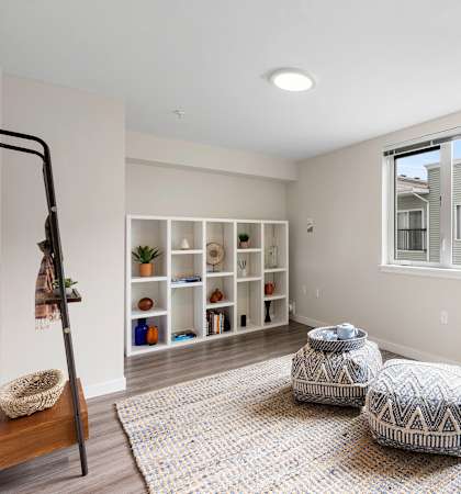 a bedroom with a large window and two stools in the middle of the room at Arabella Apartment Homes in Shoreline, WA